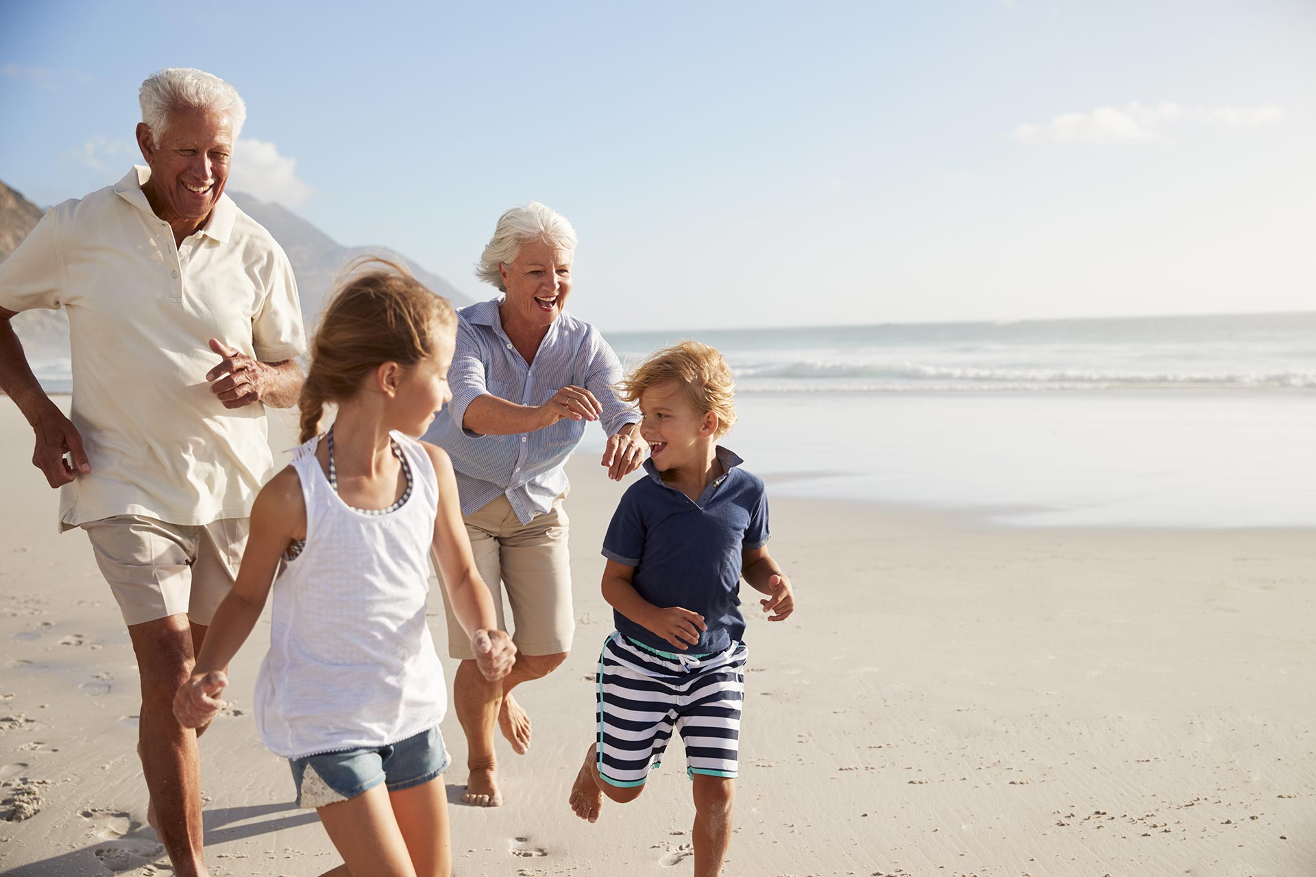 grandparents and kids running on beach
